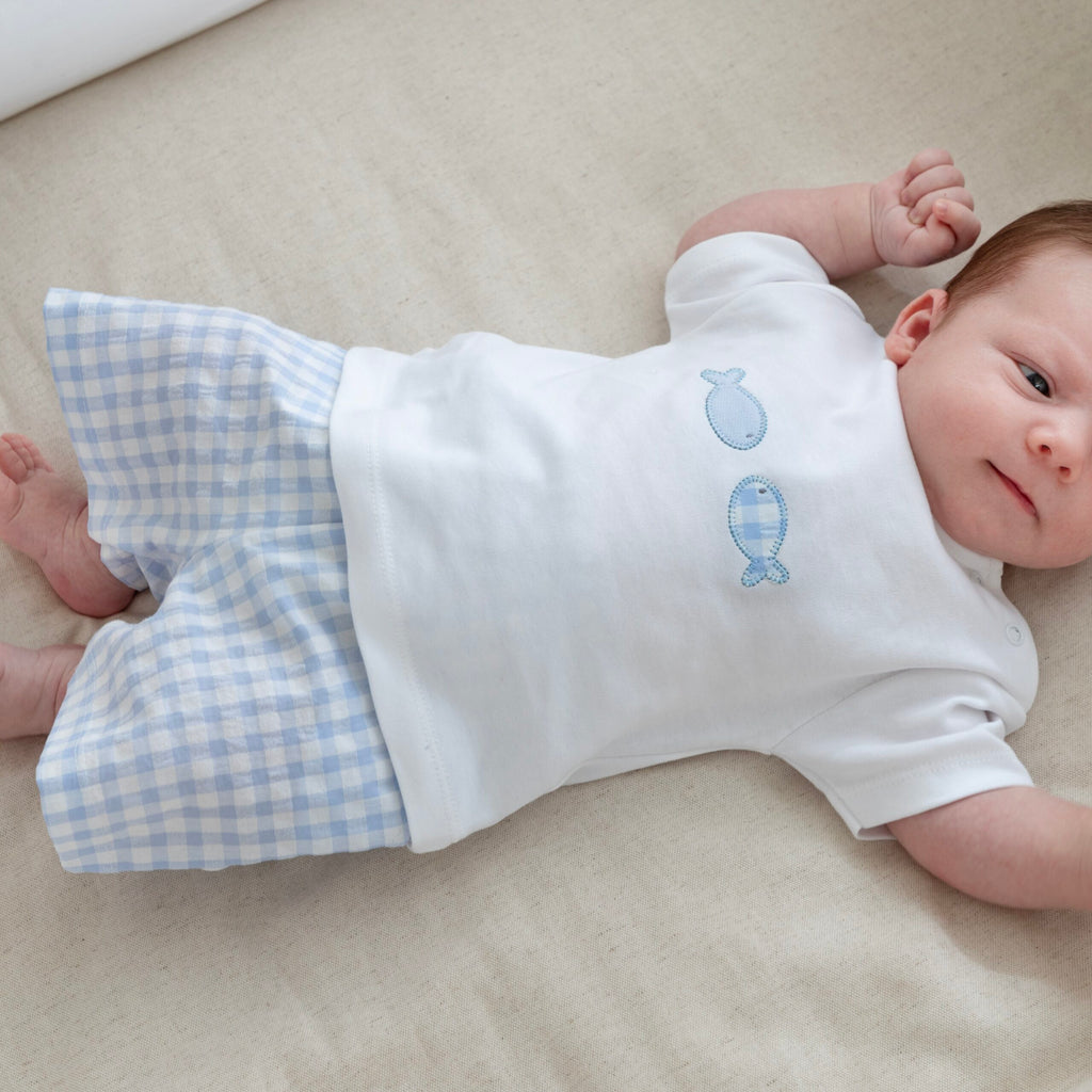 Baby in t-shirtje met twee blauwe visjes en blauw wit geruite korte broek
