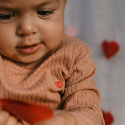 Een baby in een koraalkleurige longsleeve