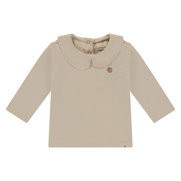 A Tiny Story Long sleeve Beige met een mooie sierlijke kraag en een donker beige klavertje voor op. In maat 50,56,62,68