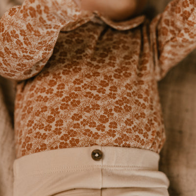 A Tiny Story Romper Newborn in beige bloemenprint. In maat 44,50,56,62,68,74.