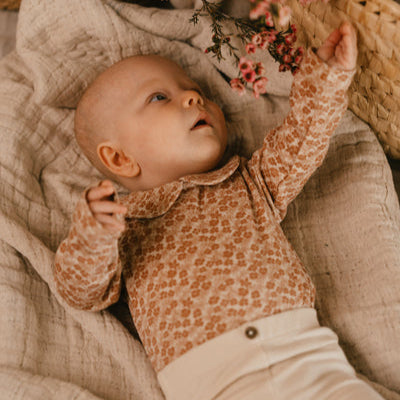 A Tiny Story Romper Newborn in beige bloemenprint. In maat 44,50,56,62,68,74.