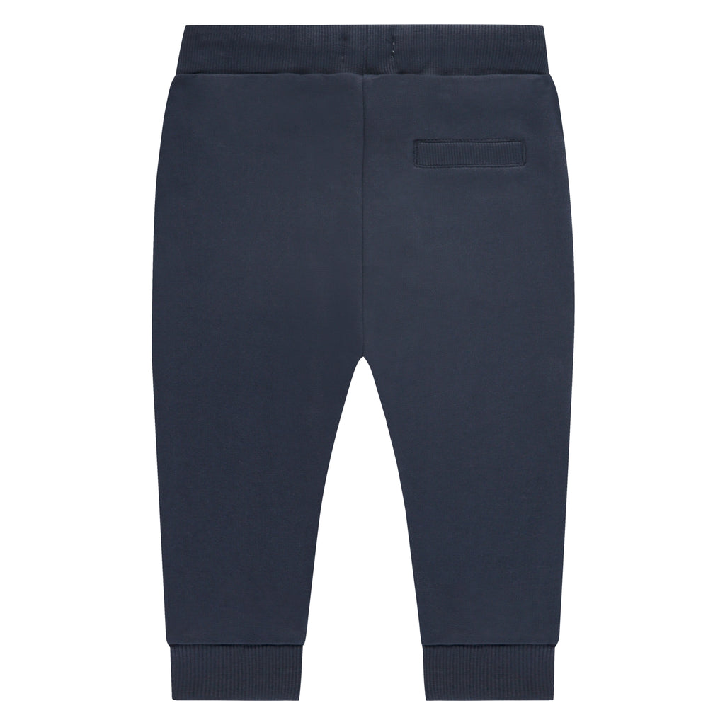 De achterkant van een donkerblauw babybroekje met een zakje op de achterkant
