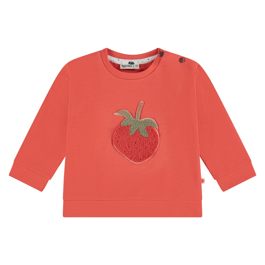 Een rode babytrui met een aardbei er op
