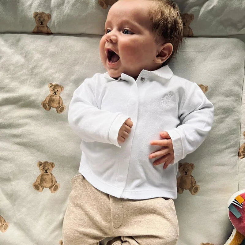 Een kindje in een beige babypakje