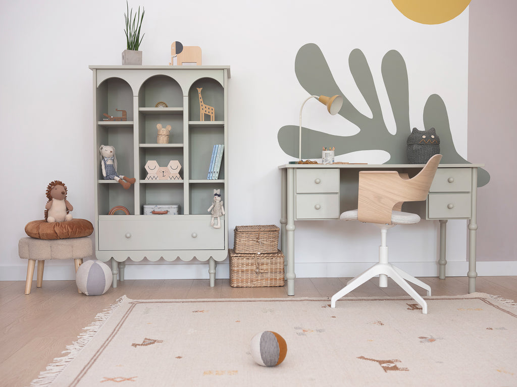 Een kinderkamer met een olijfkleurige boekenkast en olijfkleurig bureau