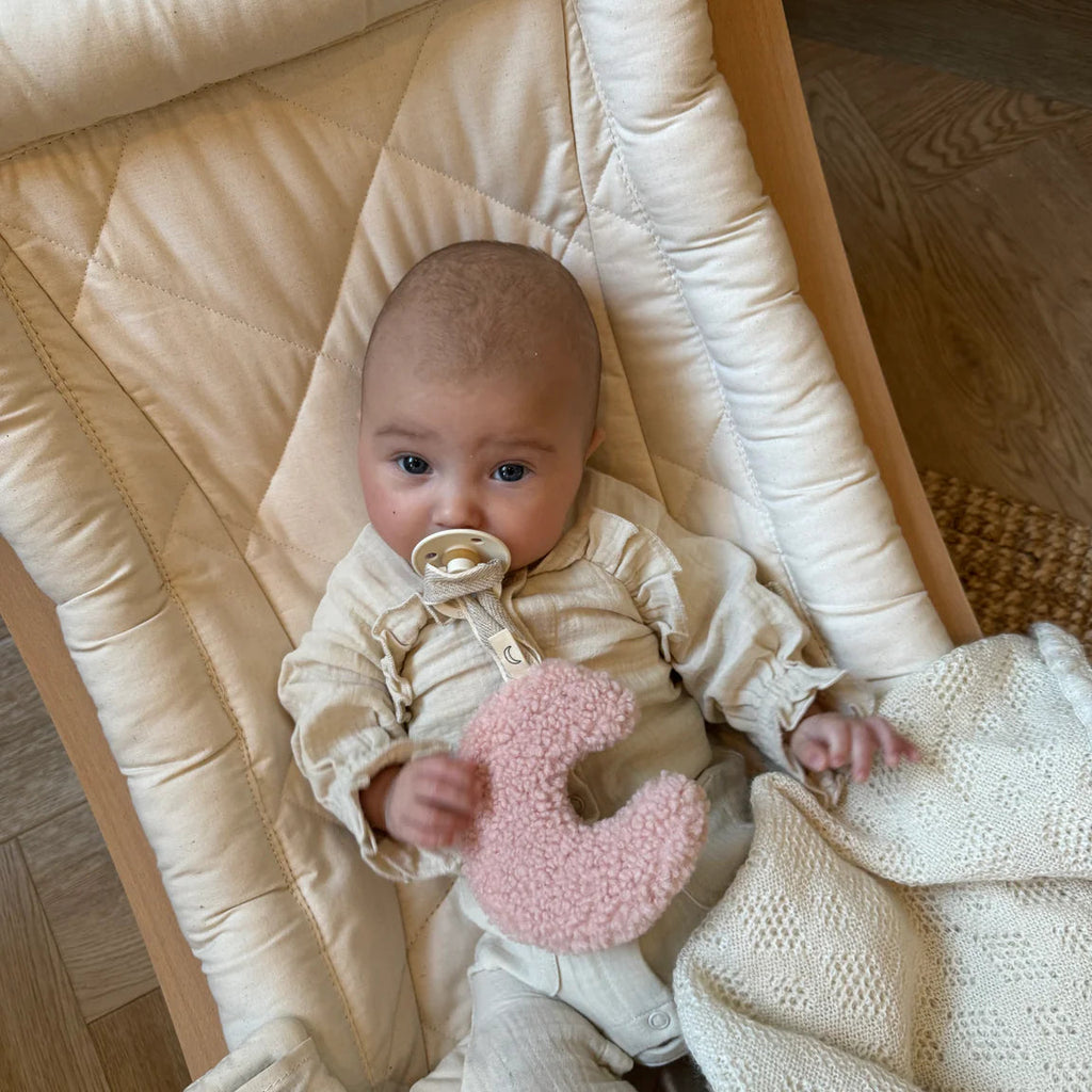 Een baby met een speentje en een licht roze speenknuffel