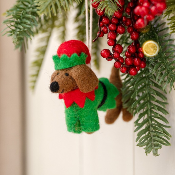 Vilten teckel hanger in een vrolijke kerstelf-outfit, compleet met puntmuts en touwtje voor eenvoudig ophangen.