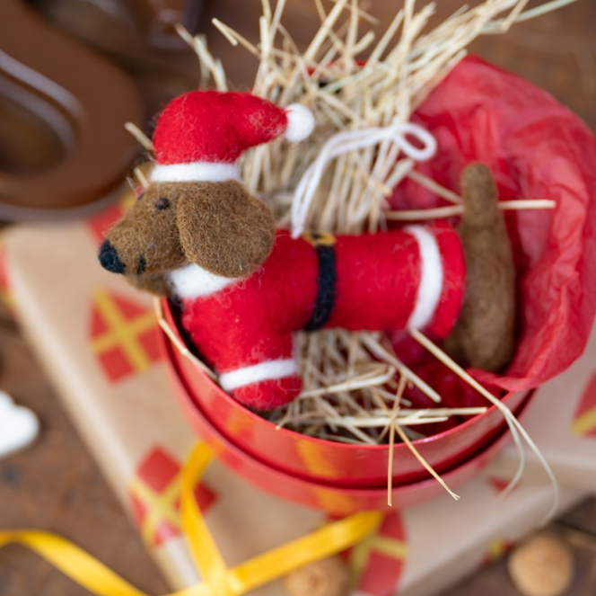 Teckel als kerstman van vilt, met rood pak en kerstmuts. 