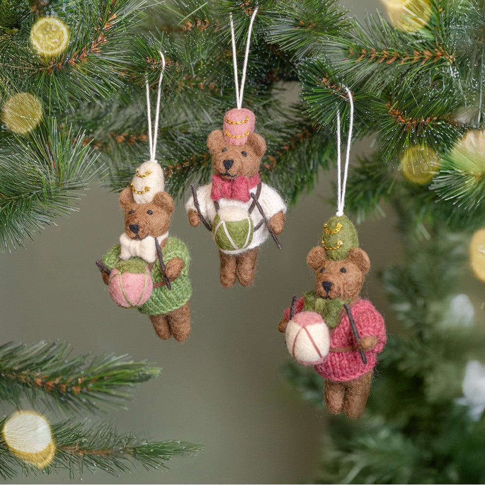 Een kerstboomhanger in de vorm van een beertje met een trommel in zijn hand. In de kleur cyclaam, groen en wit.