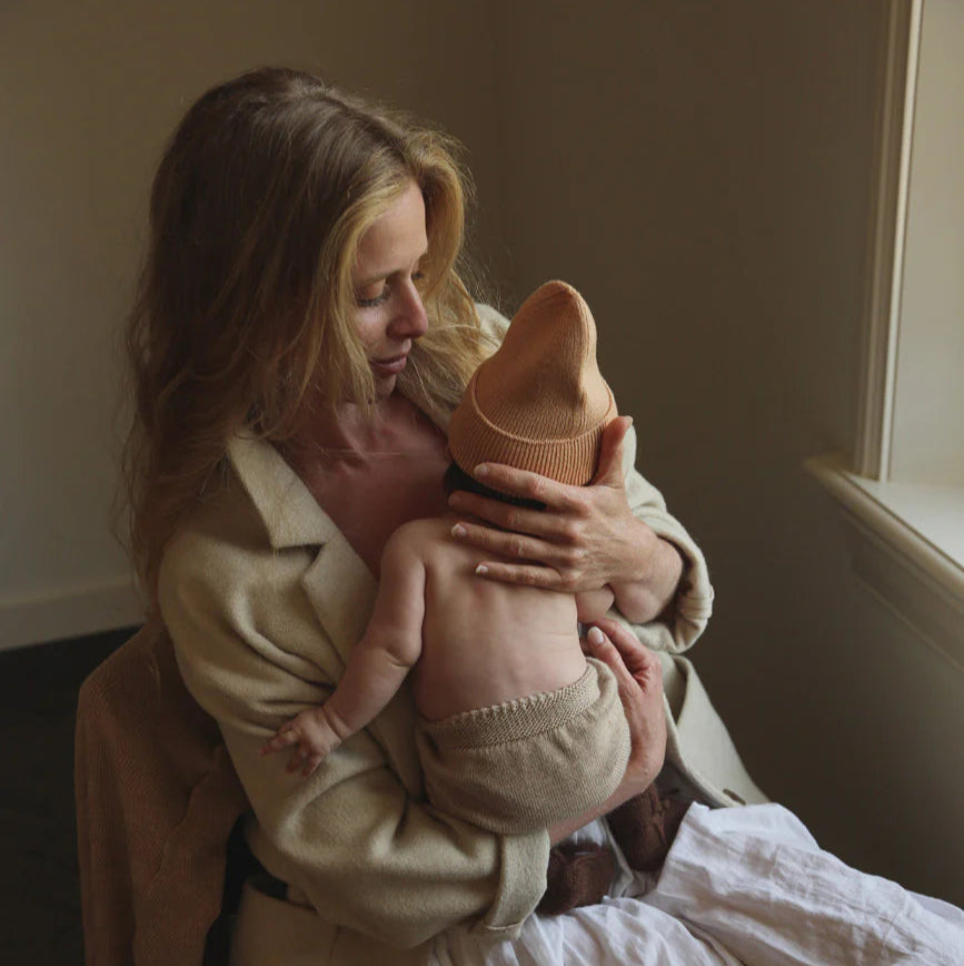 Een mama met een kindje in een beige baby broekje