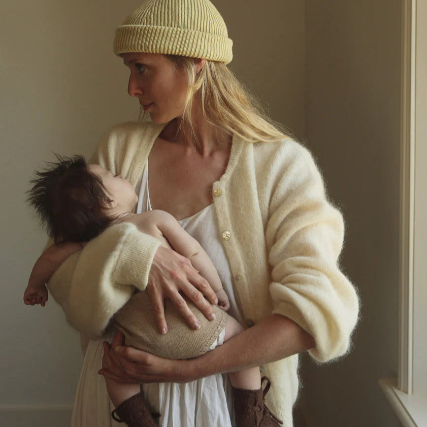 Een moeder met een baby met een beige baby bloomer