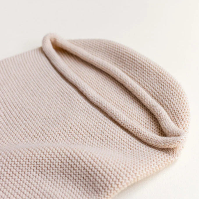 Een licht beige cocoon baby deken