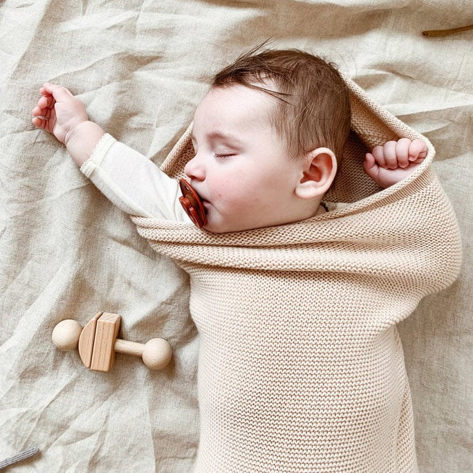 Een baby in een licht beige cocoon deken