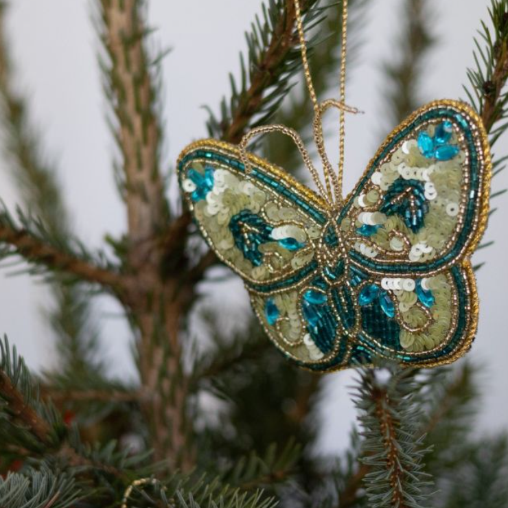 Handgemaakte hanger in de vorm van een vlinder versierd met glinsterende kraaltjes en pailletten.