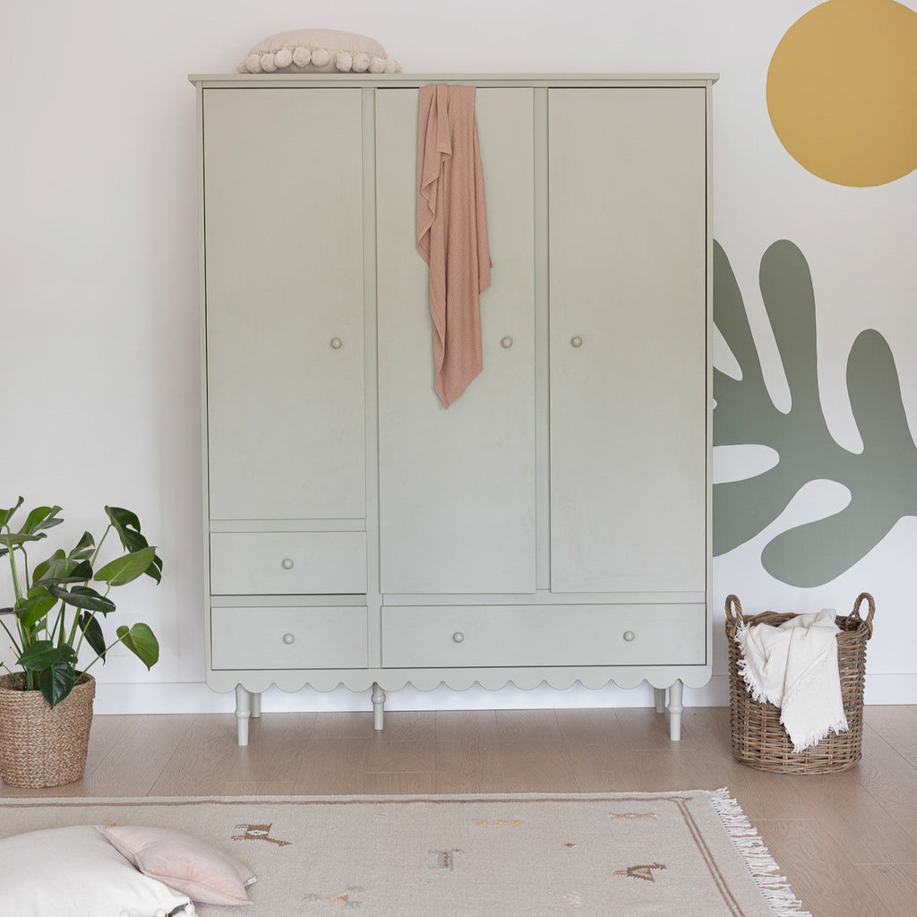 Een olijfgroene kledingkast met drie deuren in een kamer