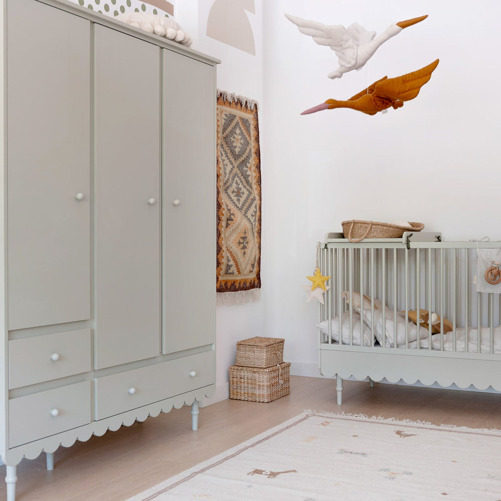 Een olijfkleurige kledingkast met 3 deuren en een olijfkleurig ledikant in een babykamer