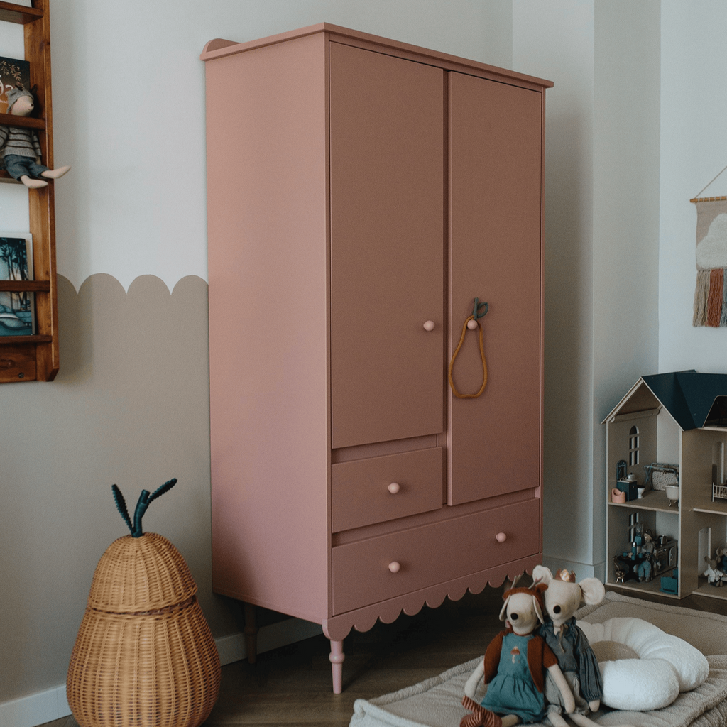 Een oud roze kledingkast in een kinderkamer