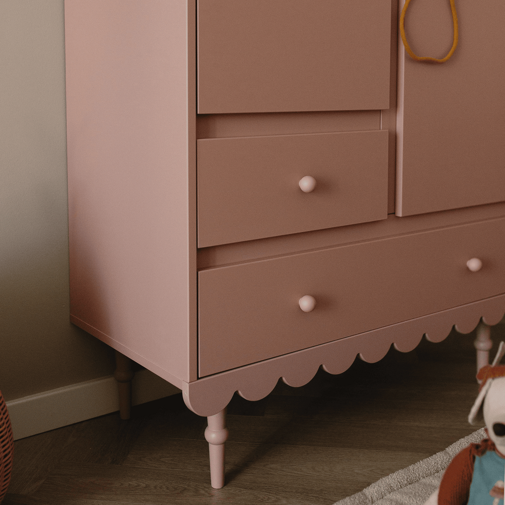 De onderkant van een oud roze kledingkast in een kinderkamer
