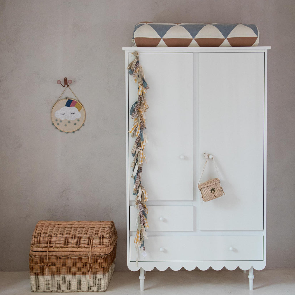 Een witte kledingkast in retrostijl in een kinderkamer
