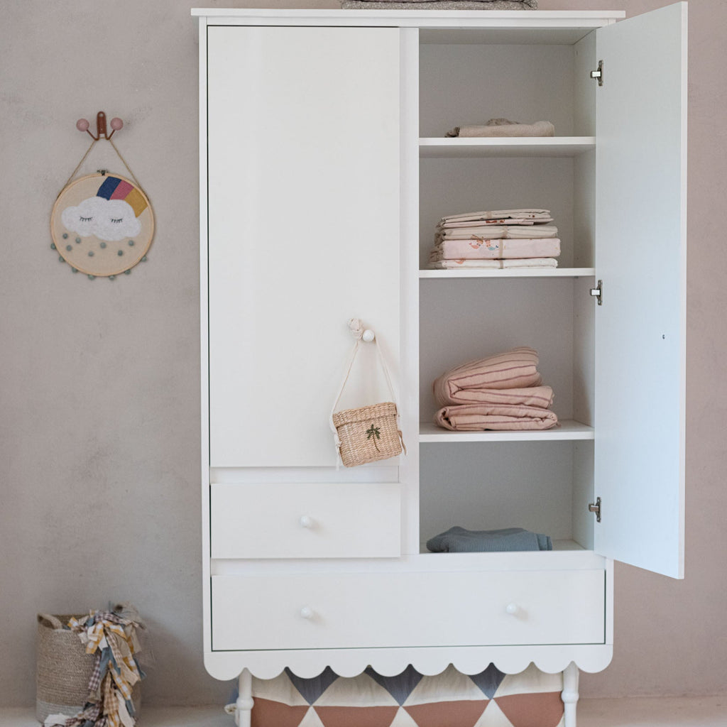 Een witte kledingkast met twee deuren en twee lades in een kinderkamer