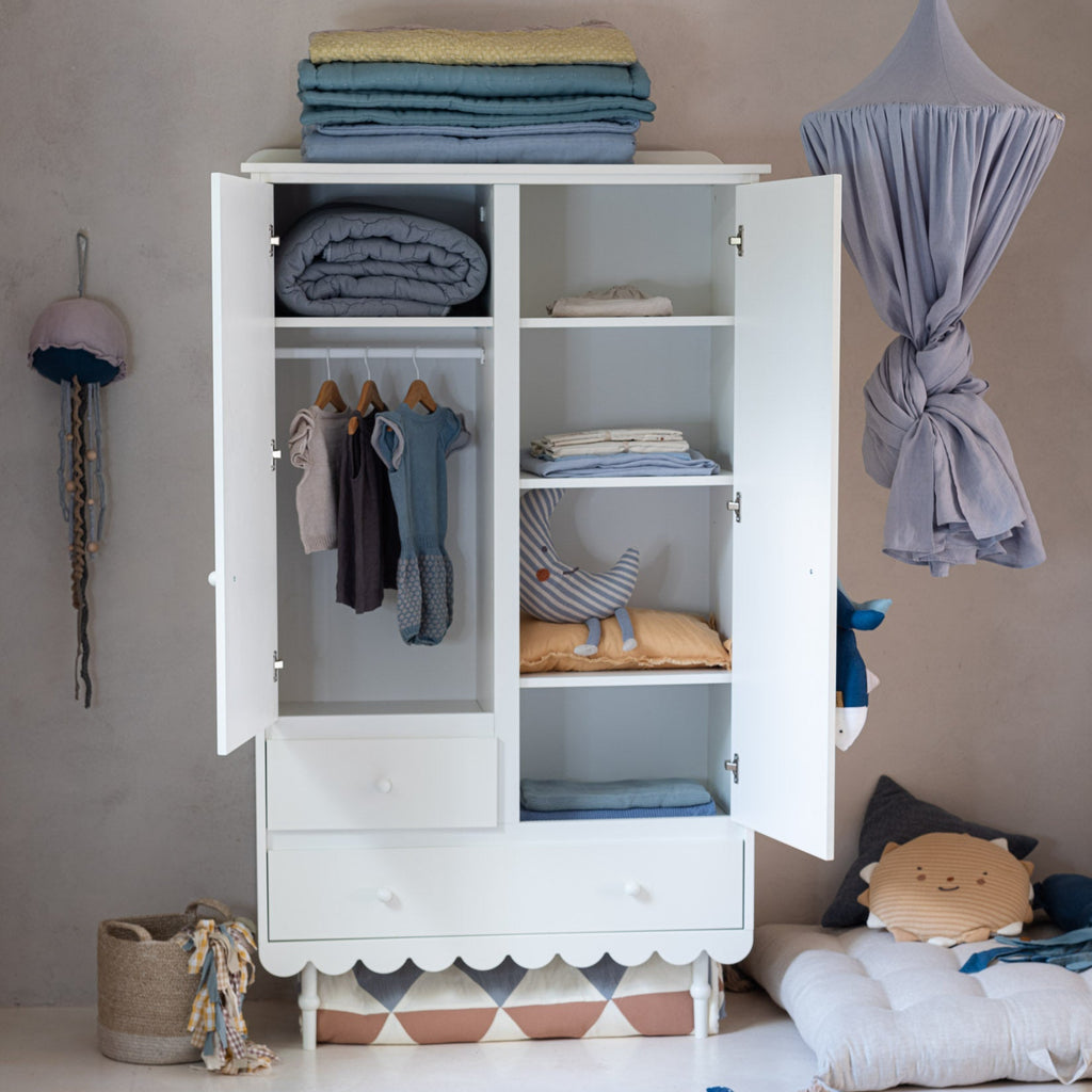 Een witte kledingkast met twee deuren en twee lades in een kinderkamer