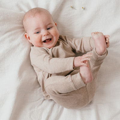 Een kindje in een beige long sleeve met overslag en een beige broekje