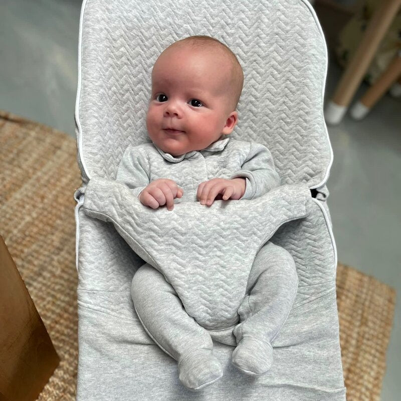 Een baby in een licht grijs boxpakje