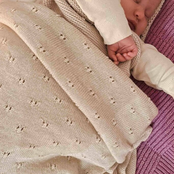 Een kindje onder een beige wiegdeken