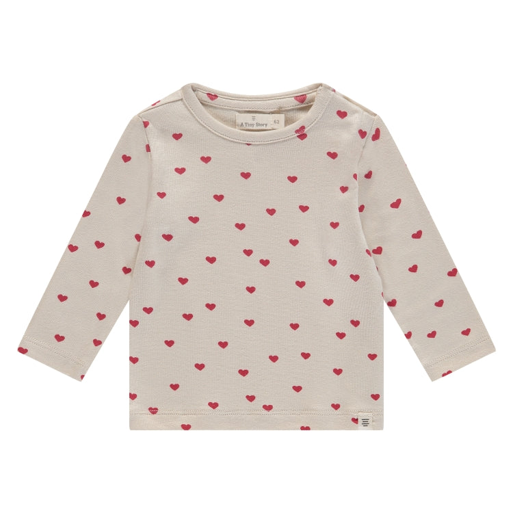 Een gebroken wit baby shirtje met rode hartjes