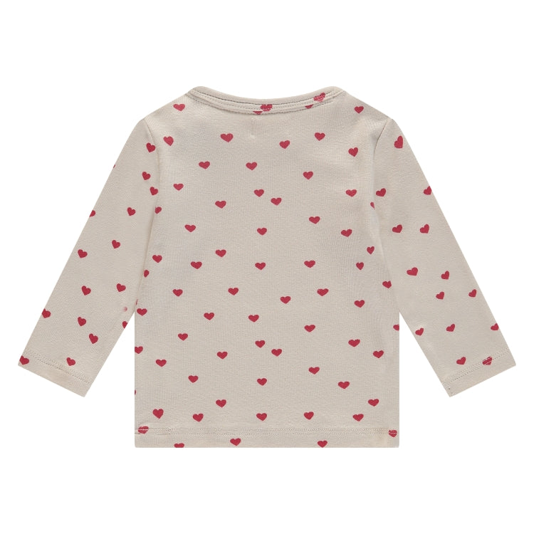 Een gebroken wit babyshirtje met rode hartjes