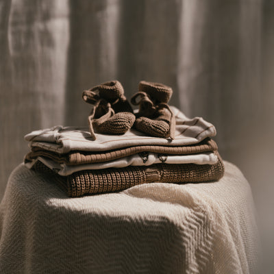 Stapeltje kleren met bruine babysokjes er bovenop