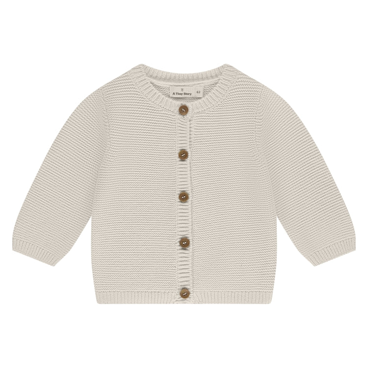 Een gebroken wit babyvestje met knoopjes