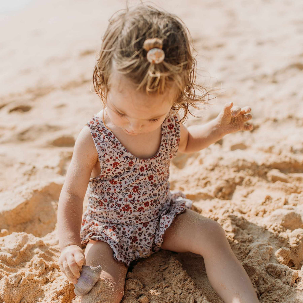 Een meisje op het strand in een gebloemd zwempakje