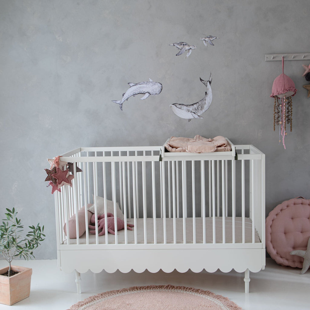 Een ledikantje in een babykamer met een wit commode opzetstuk 