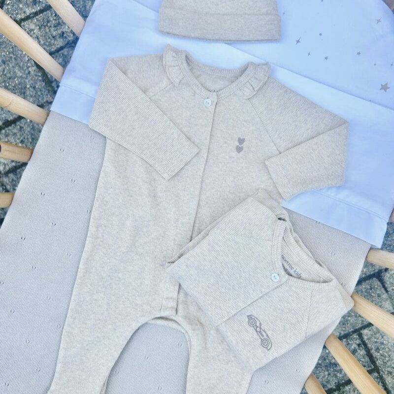 Een beige boxpakje in een wiegje
