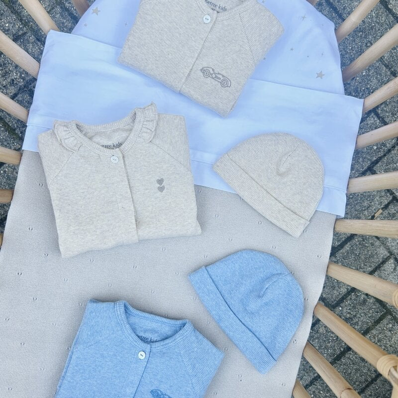 Beige en blauwe babypakjes in een wiegje