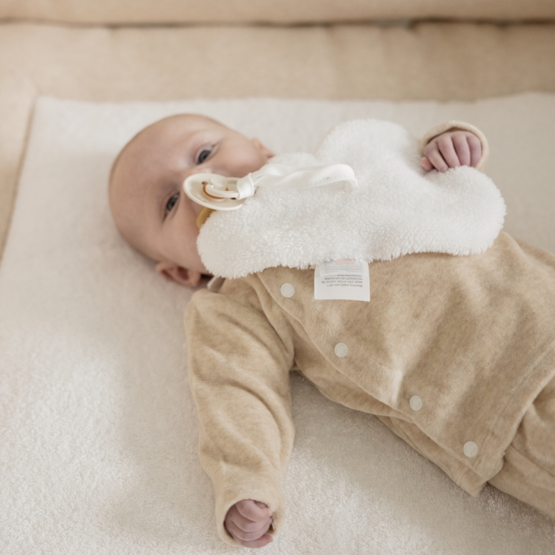 Een baby in een beige babypakje van velours