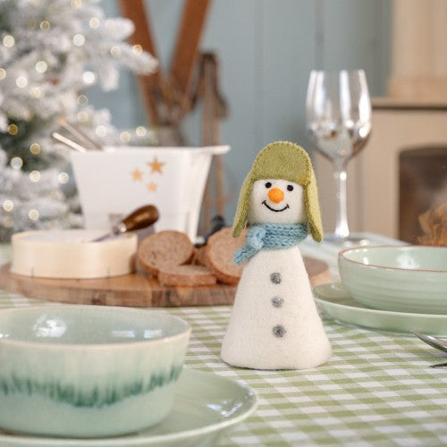 Een sneeuwpop met een groene muts en een blauwe sjaal gemaakt van wolvilt.