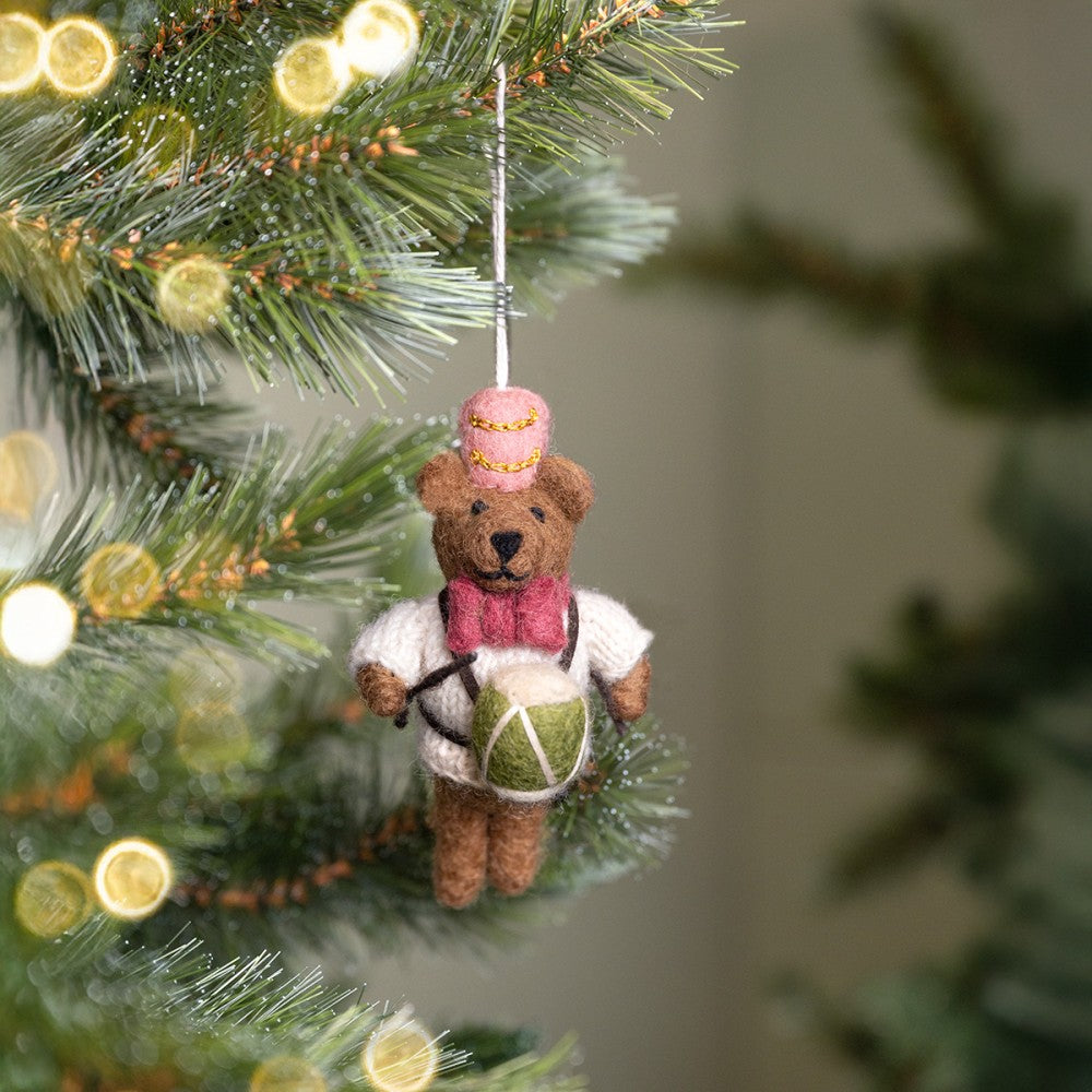 Kerstboom hanger beertje met een trommel in zijn handjes. Bruin beertje met witte trui, roze muts, roze strik en groen trommeltje.