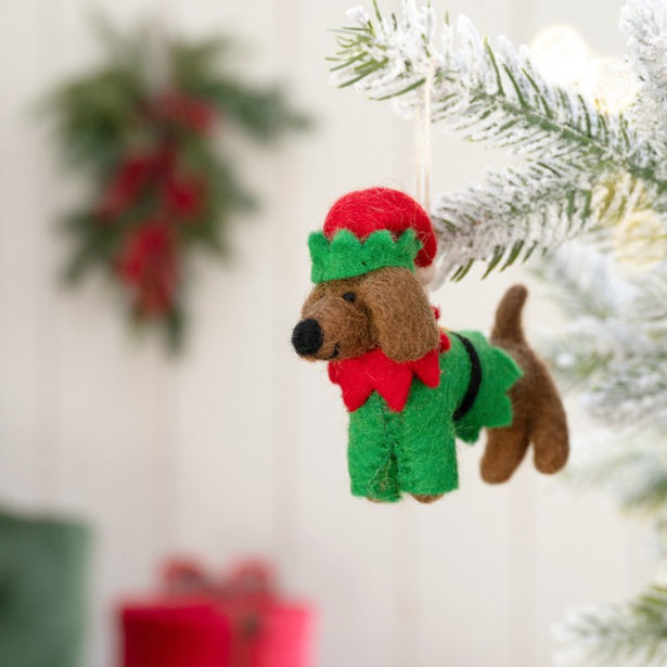 Vilten teckel hanger in een vrolijke kerstelf-outfit, compleet met puntmuts en touwtje voor eenvoudig ophangen.