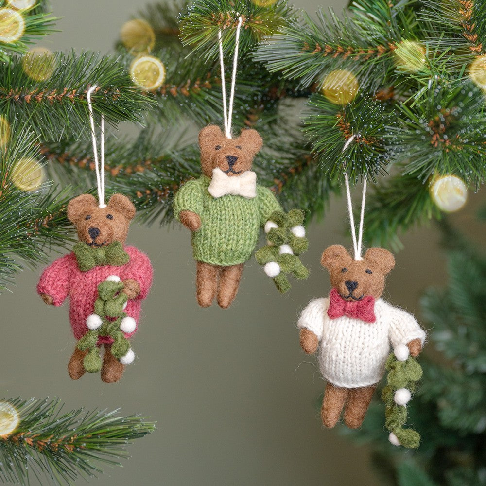 Een kerstboomhanger, beertjes in crème kleurige, groene en cyclaam kleurige trui en een takje mistletoe in zijn handjes. Gemaakt van wolvilt.