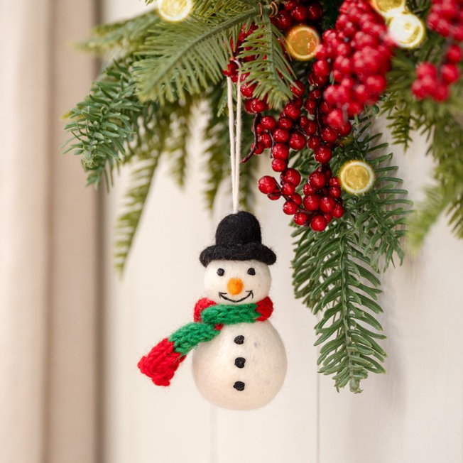 Sneeuwpop voor in de kerstboom met zwarte hoed en rood-groene sjaal.