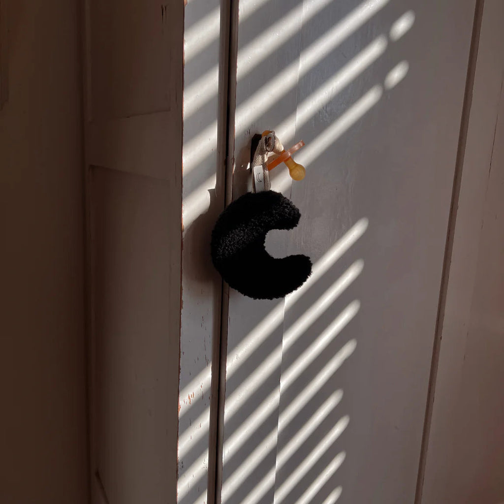 Een zwart speenknuffeltje in de vorm van een maan