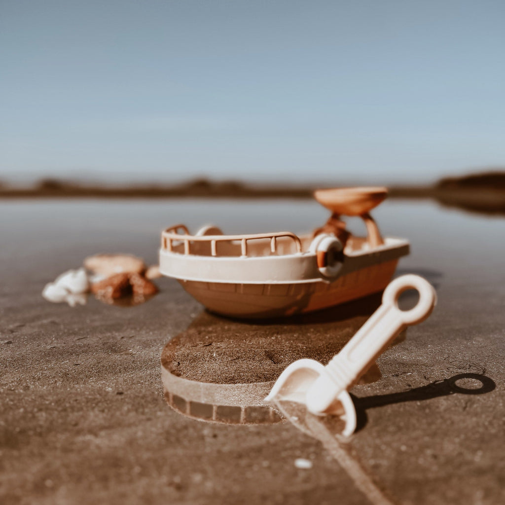 Een bootje in het water met een schepje en vormpjes.
