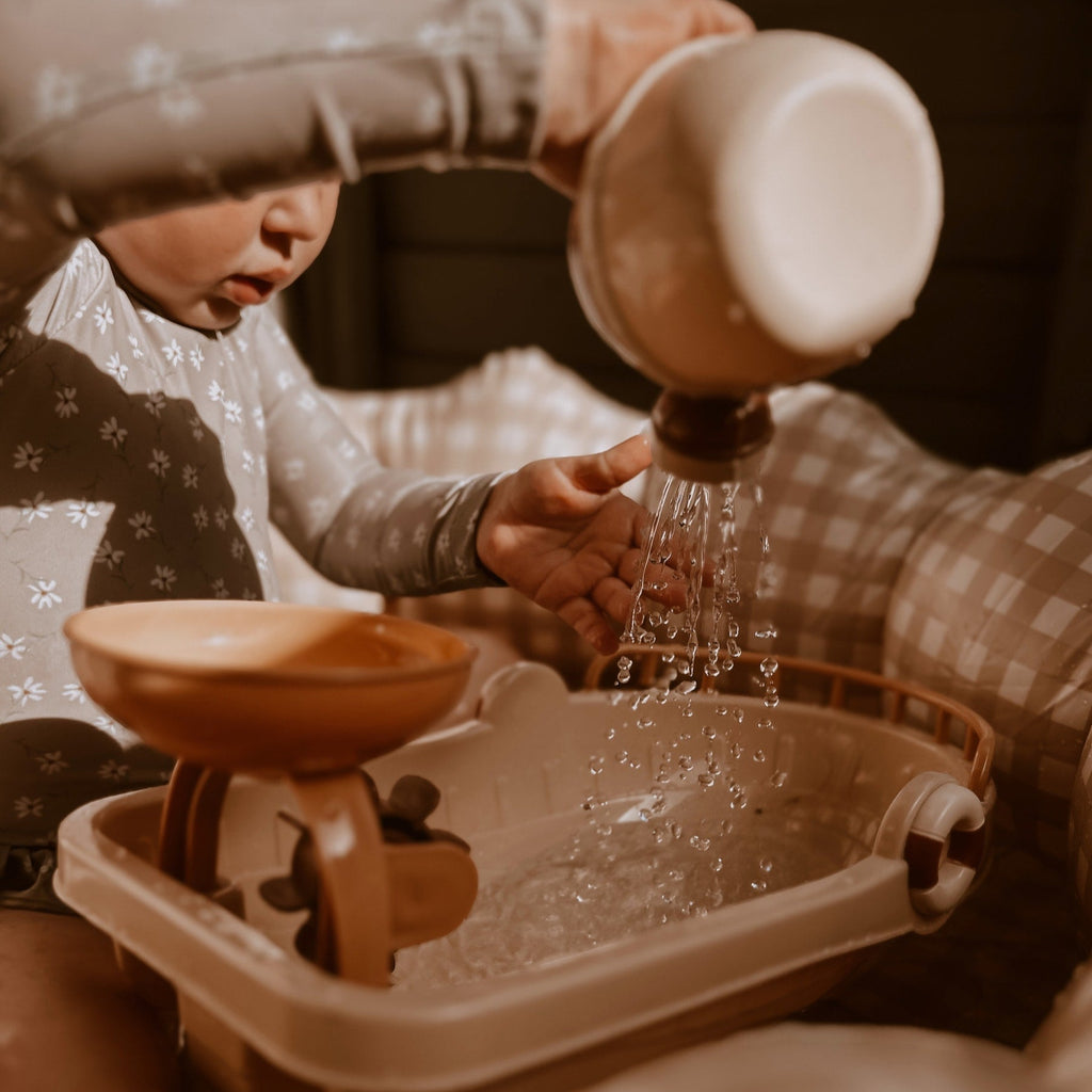 Een kindje speelt met water en een bootje