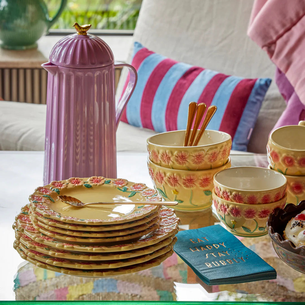 Een paarse thermoskan op tafel met servies