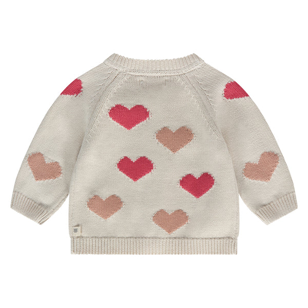 De achterkant van een gebroken wit babyvestje met koraalkleurige en rode hartjes