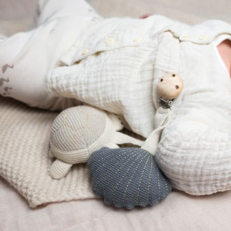 Een baby met een knuffeltje aan zijn truitje bevestigd