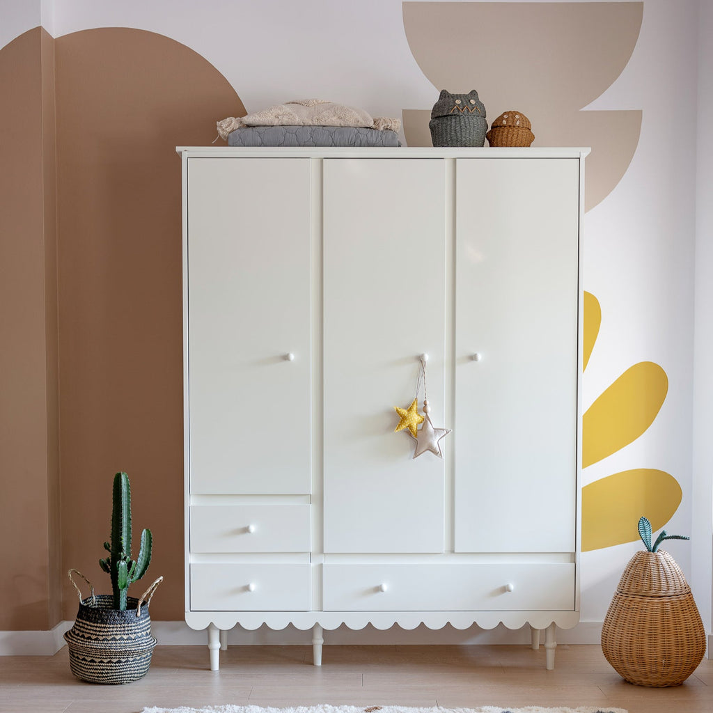 Een witte kledingkast met 3 deuren in een kinderkamer
