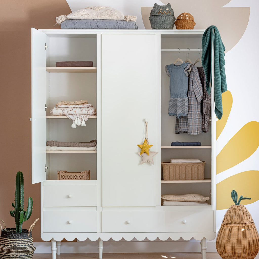Een witte kledingkast met 3 deuren in een kinderkamer